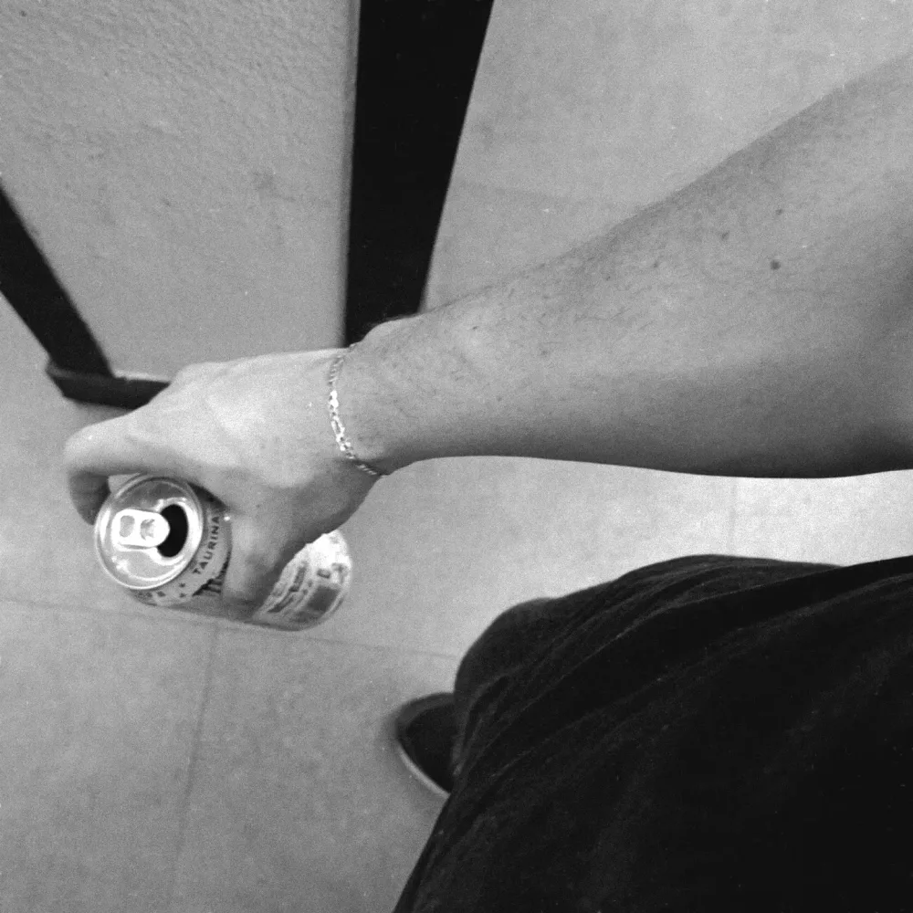 Foto em preto e branco: o braço do Professor com pulseira de prata segurando uma latinha